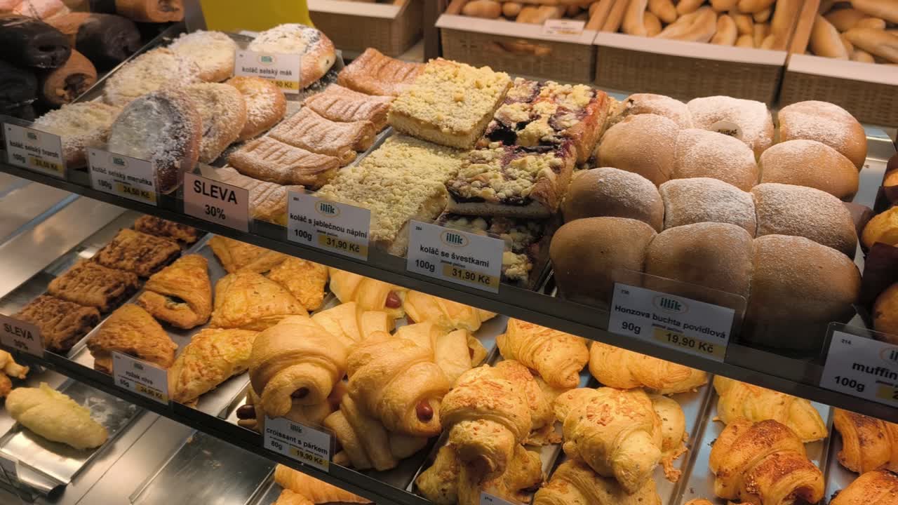 A display of assorted fresh pastries and bread inside a bakery shop in the Czech Republic, showcasing a variety of baked goods in a warm and inviting atmosphere