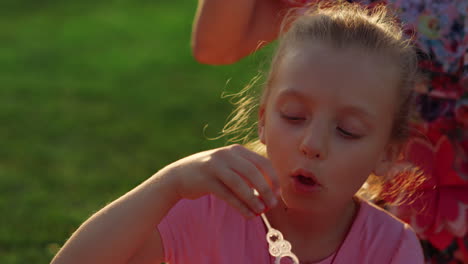 Cute-girl-relaxing-in-garden.-Female-kid-blowing-soap-bubbles-in-city-park.