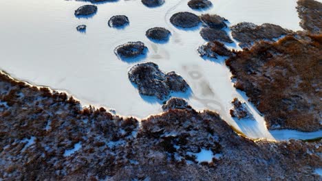 Vista-Aérea-De-Un-Lago-Congelado-En-Un-Paraíso-Invernal,-Rodeado-De-Colinas-Cubiertas-De-Nieve-Y-árboles-De-Hoja-Perenne,-Toma-Panorámica-En-órbita