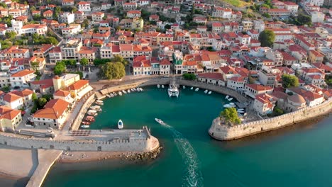 Aerial-Static-Footage-of-Nafpaktos-City-Port-Greece,-Boat-Glides-in-City-Walls,-Real-Time-Shot