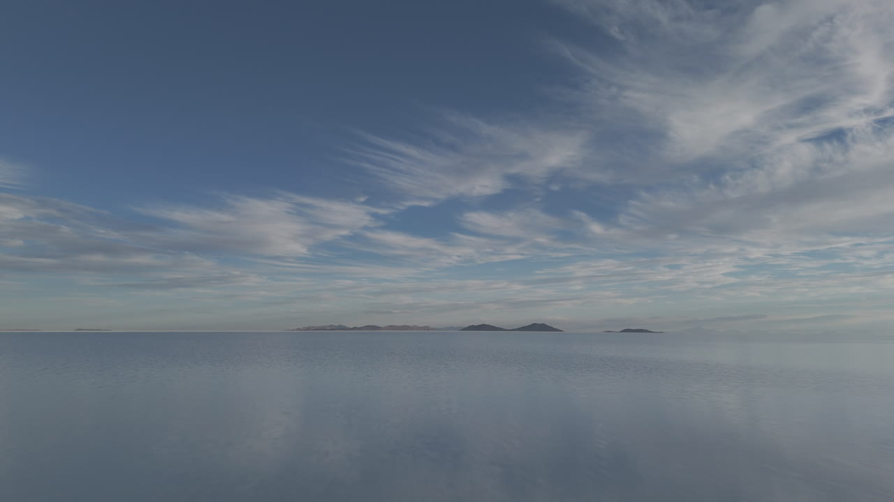 Drone shot flying above the mirror salt flats in Bolivia Uyuni on a cloudy day with the visible reflection LOG