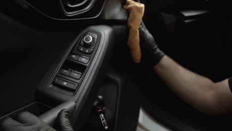 Close-up-of-a-male-wearing-black-gloves-cleaning-a-white-car-with-black-interior-with-a-microfiber-cloth-in-slow-motion