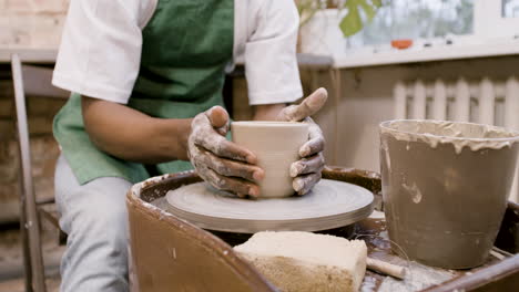 vista dal basso dell'impiegato americano che modella un pezzo di ceramica su un tornio da vasaio in un'officina