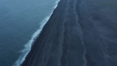 Vista-De-Arriba-Hacia-Abajo-De-La-Playa-Negra-De-Dyrholaey-Cerca-De-Vik-En-Islandia.-Vista-Aérea-Del-Majestuoso-Lugar-Del-Tormentoso-Océano-Atlántico-Y-La-Playa-De-Arena-Negra-Volcánica