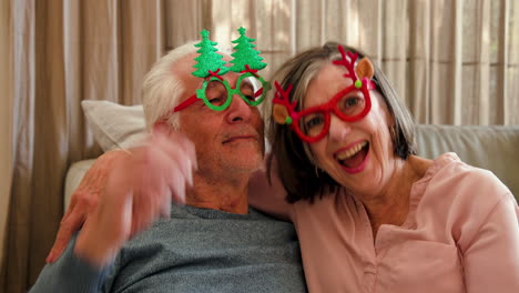senior couple wearing festive glasses, enjoying christmas at home, smiling together