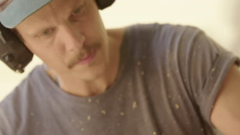 close-up on concentrating woodworker with earmuffs covered in wood shreds