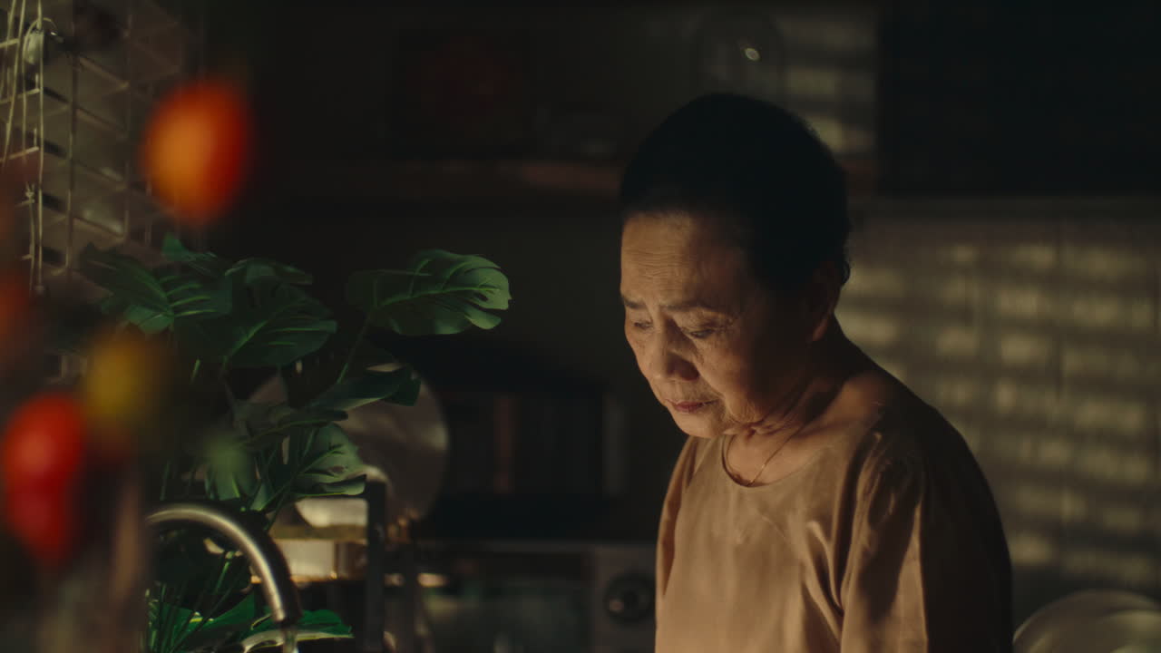 Sad woman standing alone in the kitchen, looking down with a contemplative expression