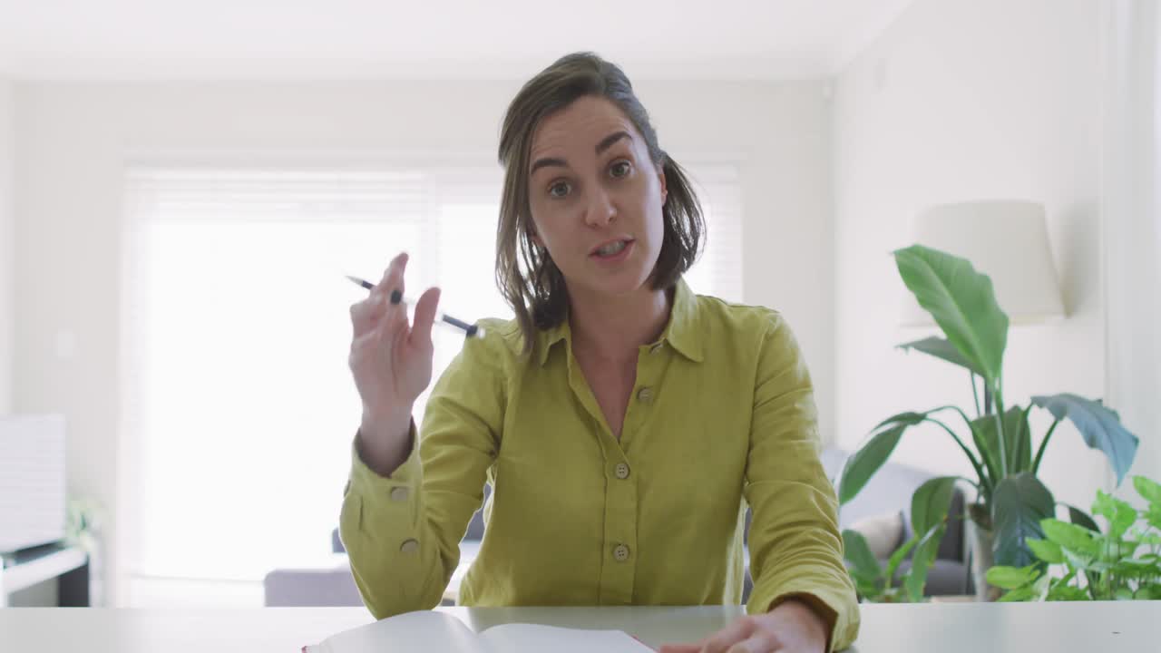 mujer caucásica con camisa amarilla haciendo una videollamada