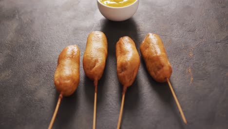 video of corn dogs with dip on a black surface