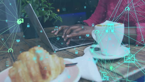 animation of connected media icons over african american woman using laptop at cafe