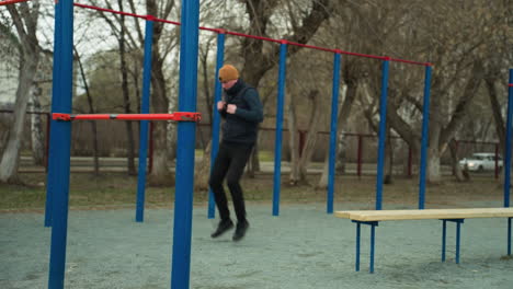 a coach jogs quickly in a stadium, surrounded by blue and red poles, with a bench nearby, with a blurred view of white car passing by with it headlight