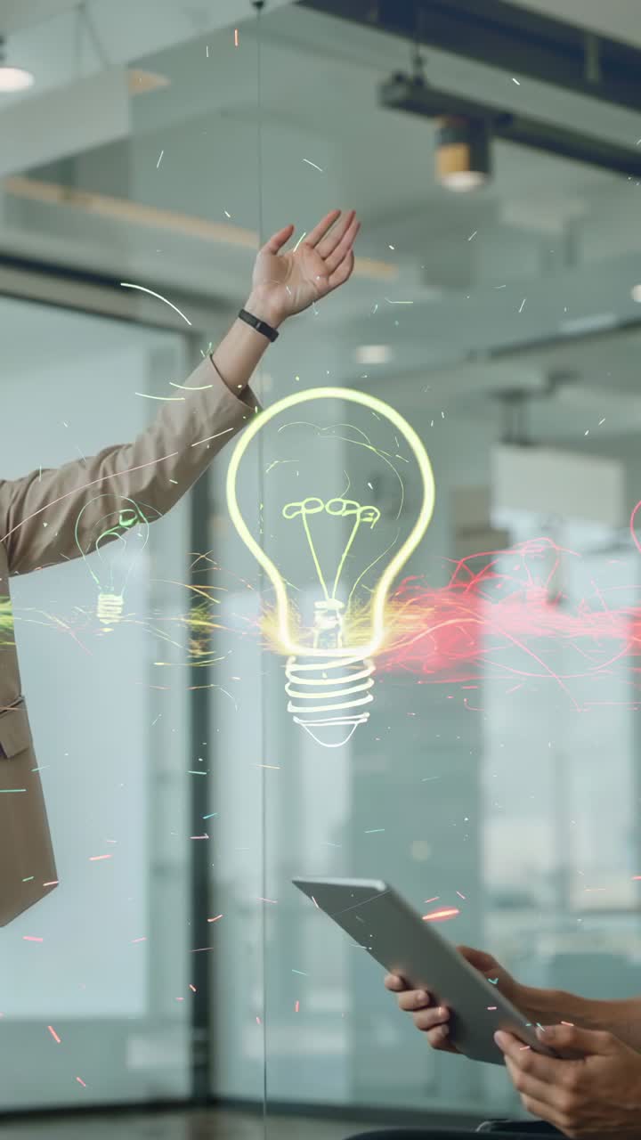 Vertical video: Office glow sparking man swiping hologram bulb for ideas, colleague tilting tablet
