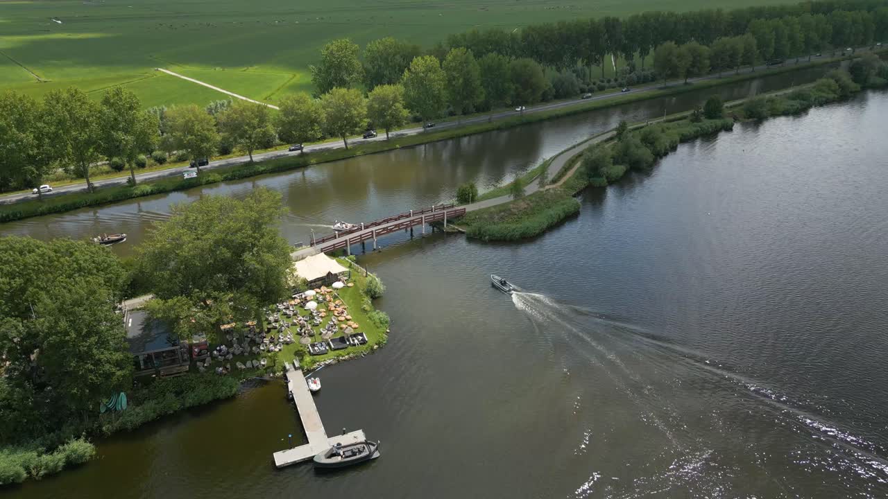 Drone view of a small pier and speedboat on a lake in Alphen aan den Rijn, surrounded by farmland and green dikes