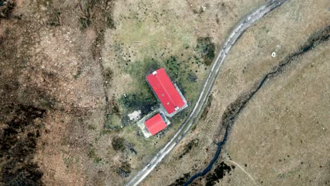 A-drone-slowly-descends-towards-the-red-roof-of-a-remote-bothy-in-the-highlands-of-Scotland