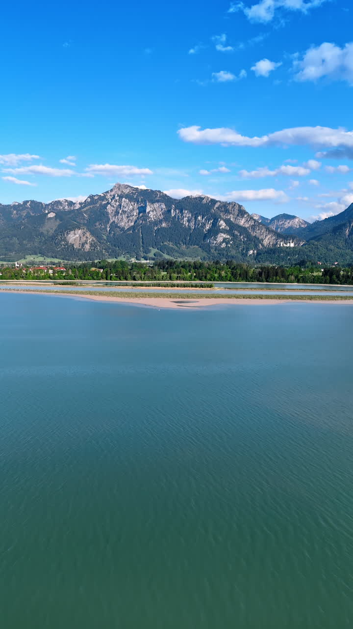 Rising over the turquoise waterscape with breath-taking view of mountains at backdrop. Nature scenery of Lichtenstein, Europe. Vertical video.