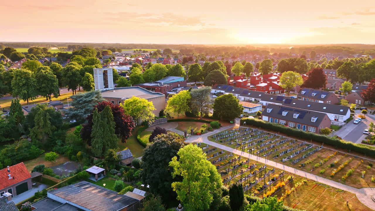 Sunset over peaceful village landscape. Golden sunlight fills the sky over a serene village, highlighting green trees and well-kept gardens at dusk
