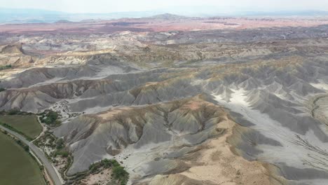 Vista-Aérea-Del-Parque-Nacional-Del-Desierto-De-Utah,-Camino-Detrás-De-Las-Colinas-De-Arenisca-Del-Paisaje-Desértico-En-El-Condado-De-Wayne-Cerca-De-Factory-Butte