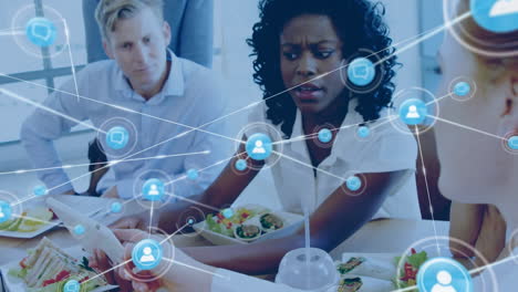 animation of network of digital icons over diverse businesspeople discussing while having lunch
