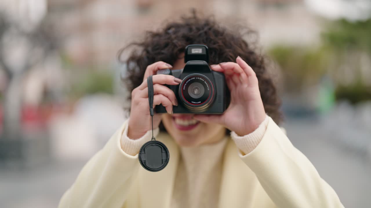 길거리에서 전문적인 카메라를 사용하여 자신감 있게 미소 짓는 젊은 여성