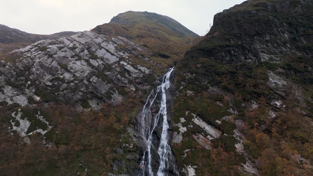 Panoramica verso l'alto dalla base delle cascate di Steall che sale per rivelare una cima montuosa rocciosa oltre