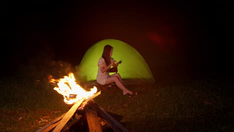 Mujer-Charlando-Al-Aire-Libre-Frente-A-Una-Hoguera-Mientras-Acampaba-Por-La-Noche-En-Un-Destino-Remoto