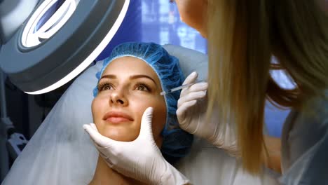 médico insertando una inyección facial en la cara de la paciente femenina