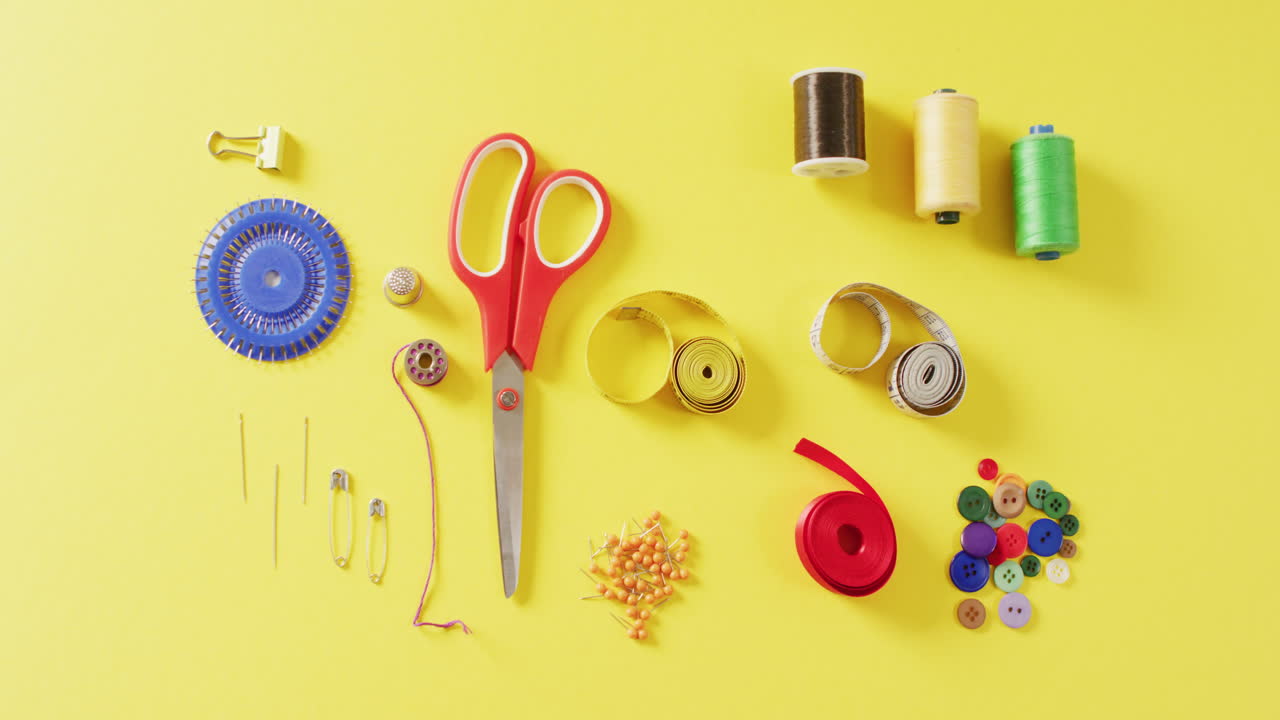 vídeo de cintas métricas, agujas, alfileres, tijeras, botones y hilos de coser sobre fondo amarillo
