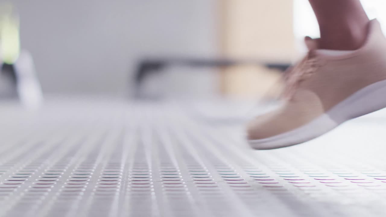 Video of low section of african american woman doing lunges with kettlebells at gym