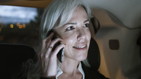 smiling woman in suit talking on phone in car