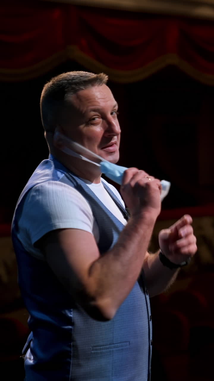 Actor puts facial mask off and annonces beginning of thater season beginning. Happy man on stage. Vertical video