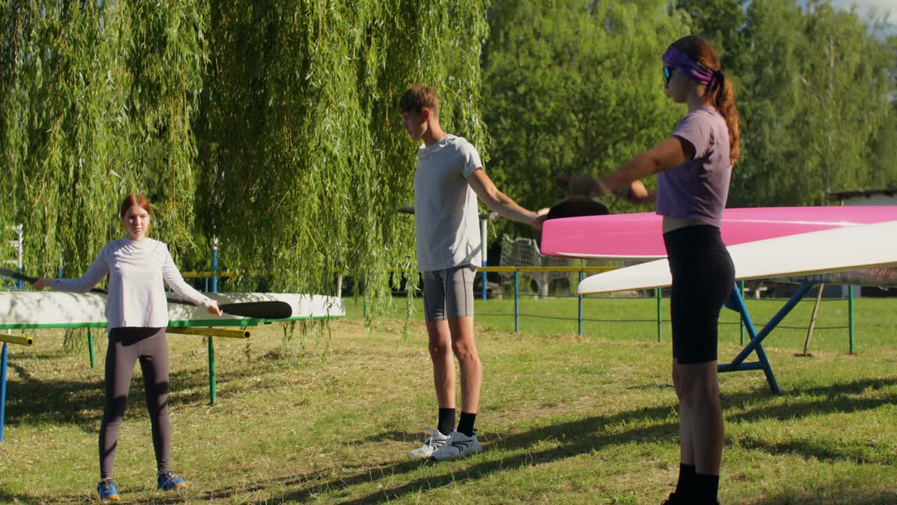 Personer som stretchar med paddlar nära kanoter
