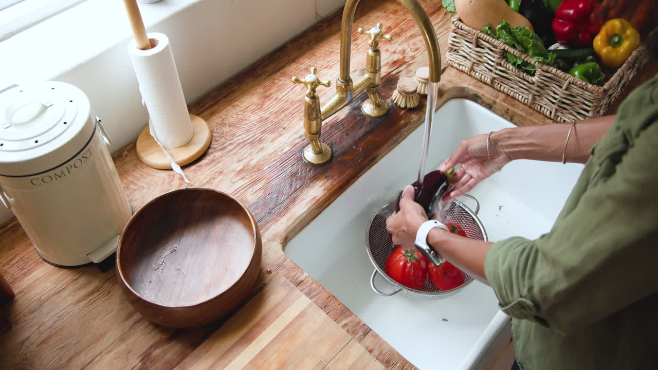 Washing fresh tomatoes in kitchen sink, preparing ingredients for cooking, at home