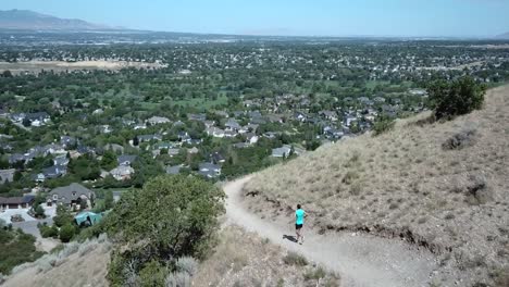 drone shot following an active man running on the outdoor mountain trails above draper city, utah-1