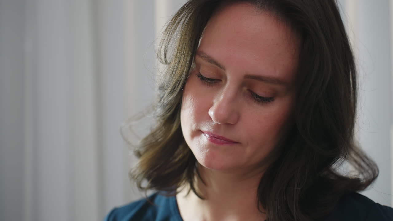 Skin care therapist concentrates with calm focused expression while performing facial treatment, illuminated by ring light, conveying professionalism and serene clinical ambiance during spa service