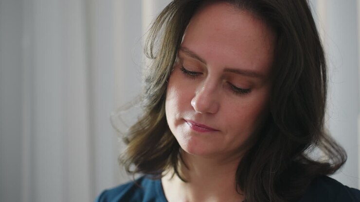 Skin care therapist concentrates with calm focused expression while performing facial treatment, illuminated by ring light, conveying professionalism and serene clinical ambiance during spa service