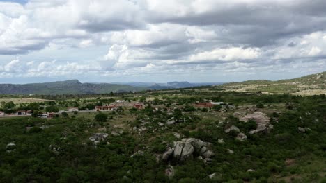 Rising-aerial-drone-shot-of-the-beautiful-green-and-rocky-countryside-of-Sítio-Novo,-Brazil-in-the-state-of-Rio-Grande-do-Norte-with-small-rural-homes-and-farmland-and-miles-of-untouched-land