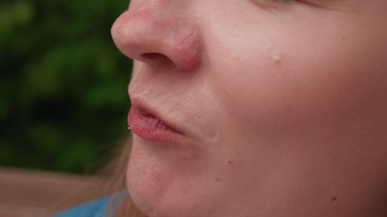 primer plano extremo de una mujer comiendo plátano crudo en el exterior; iluminación natural suave que enfatiza la textura de la fruta y la suavidad de los labios; ambiente tranquilo al aire libre que simboliza la salud