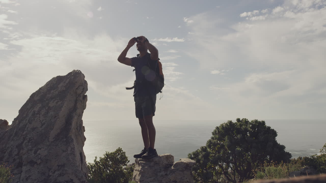 hombre caminando en la cima de una montaña con vista al océano