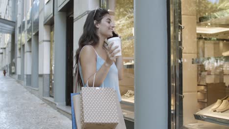 Brunette-woman-talking-on-cellphone,-drinking-takeaway-coffee