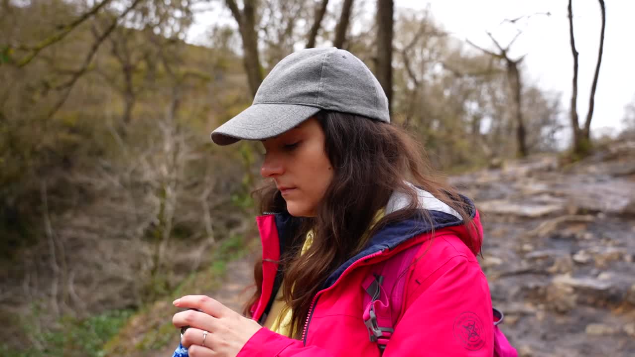 mujer abriendo una botella de metal para beber mientras camina en el bosque