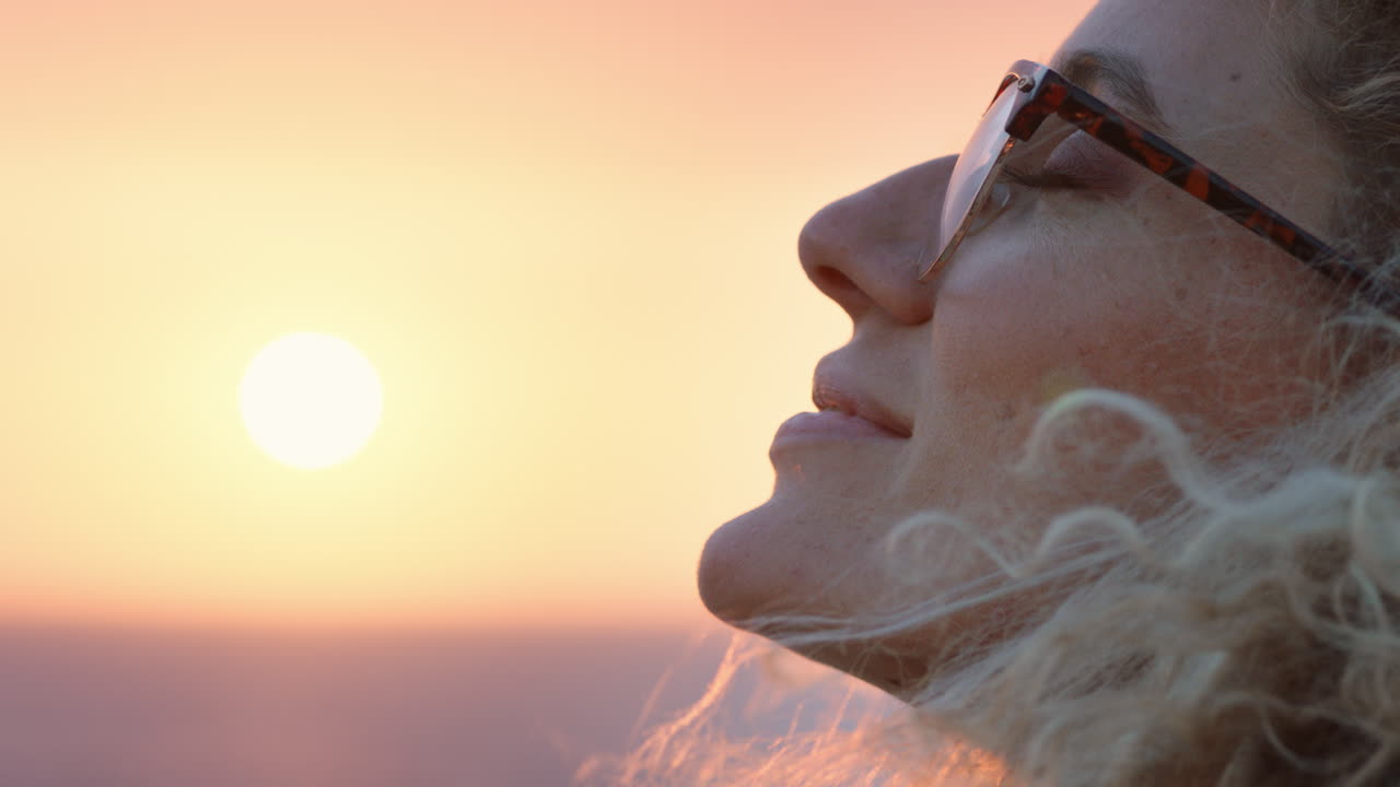 retrato en primer plano de una hermosa mujer rubia disfrutando de la tranquilidad de la playa al atardecer contemplando el viaje explorando la espiritualidad sintiendo la libertad con el viento soplando el cabello