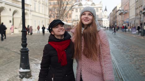 women tourists taking selfie photos on mobile phone with adoption child girl on winter city street