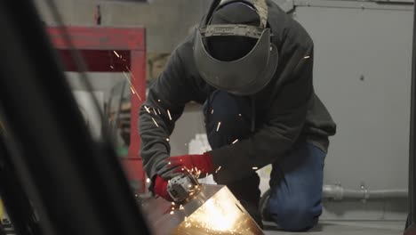 Metal-worker-wearing-PPE-cutting-metal-with-handheld-saw-in-workshop,-sparks-flying-in-slow-motion