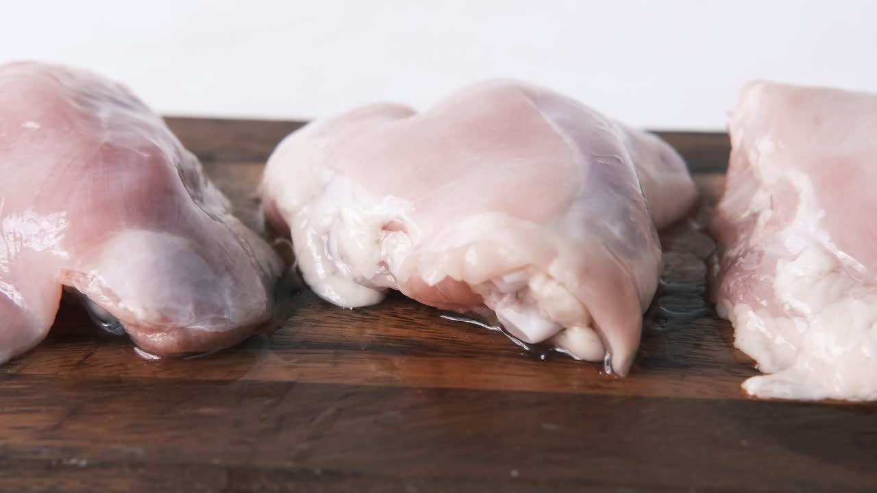 Pollo crudo su tagliere di legno.