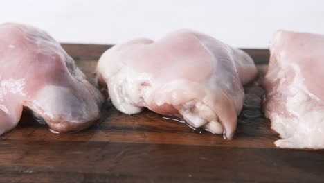 pecho de pollo crudo en una tabla de cortar de madera