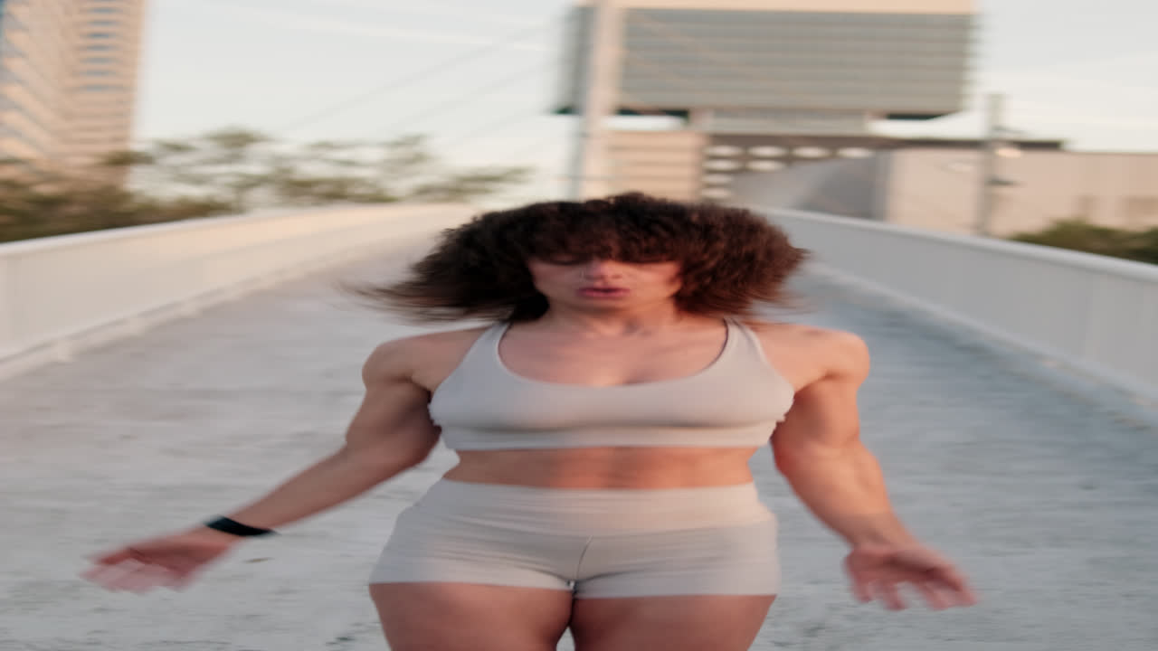 Woman Doing Jumping Jacks on City Bridge