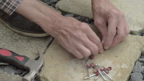 workman hands preparing nails with nail hook cable clip on concrete floor