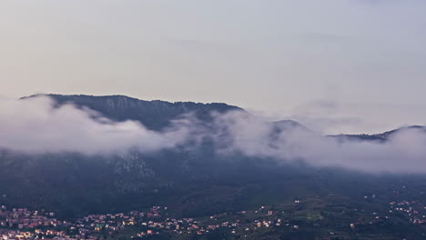 Weiße-Wolken-Ziehen-über-Der-Stadt-Mit-Einer-Bergkette-Im-Hintergrund