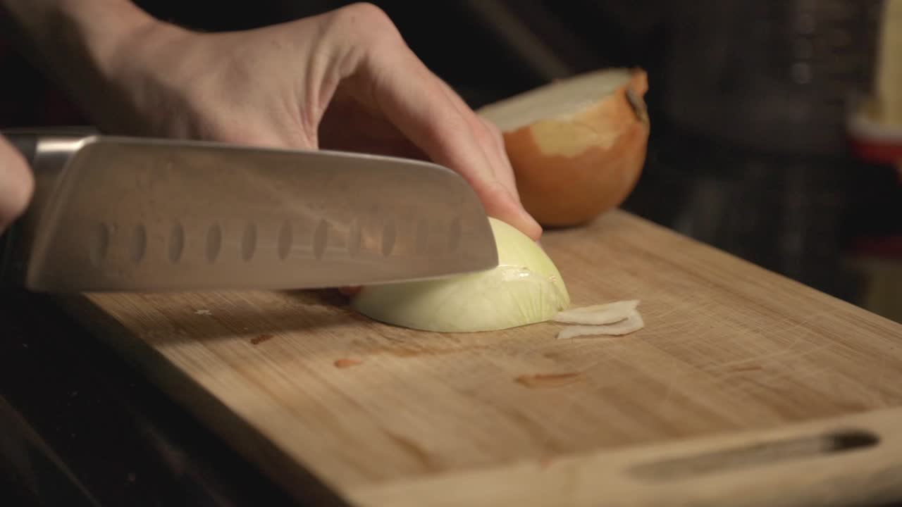 Chopping A White Onion Into The Wooden Chopping Board For Cooking