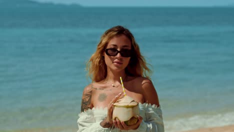 mujer disfrutando de una bebida de coco en la playa